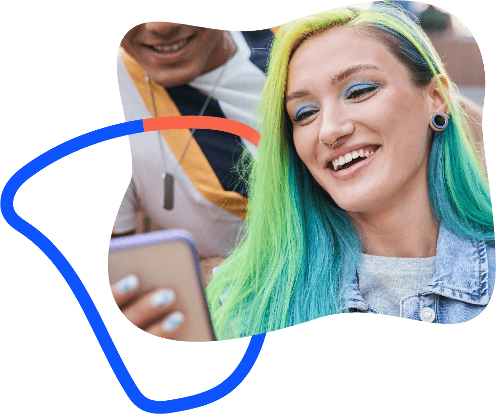 Teenage girl with yellow, green, and blue hair looking at mobile device and smiling