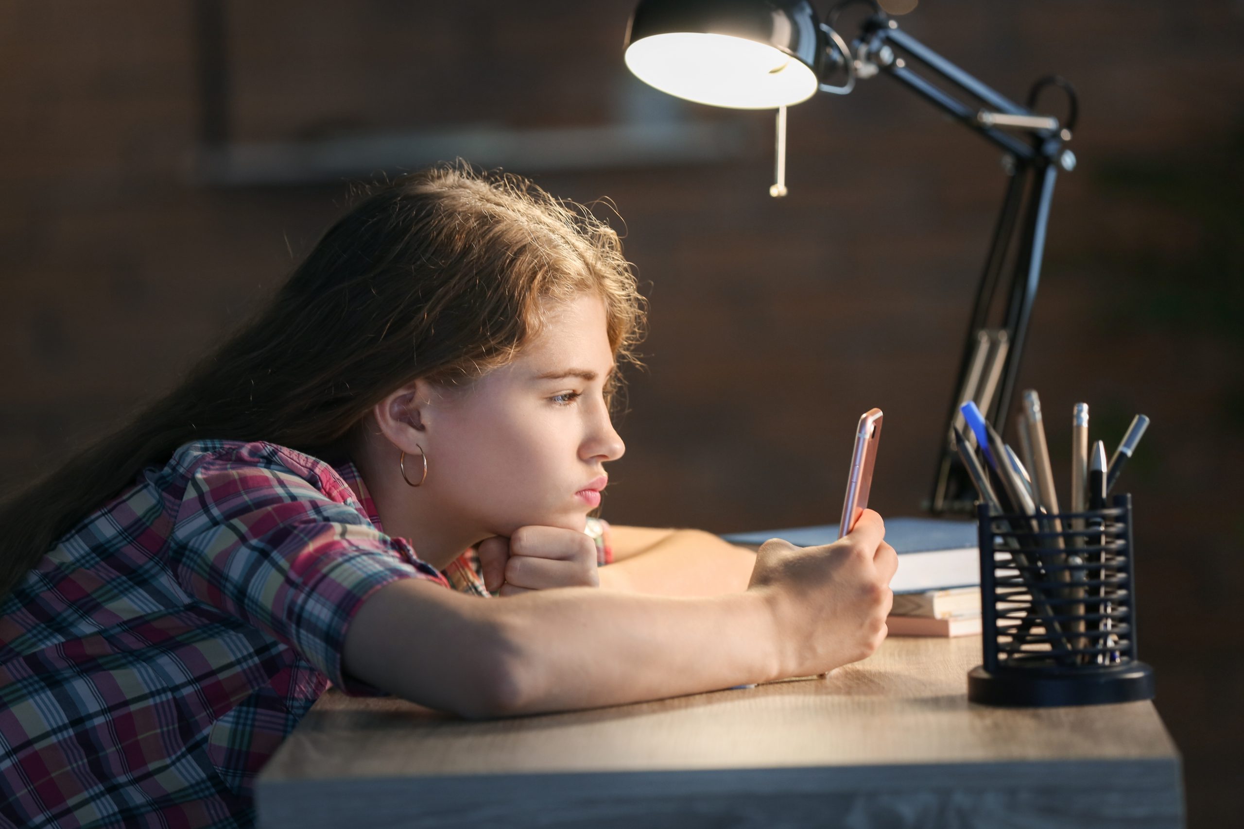 Teenage girl in chequered shirt looking at her smartphone